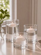 Three glass candle holders with floating candles on a reflective surface.
